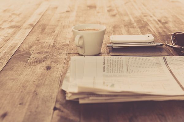 A warm vintage morning setup with coffee, newspaper, and smartphone on wooden table. — Die Spielerfahrung bei Beep Beep Casin