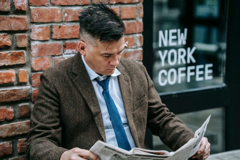 Man in formal attire reading a newspaper outside New York coffee shop. — Fgfox Casino profondeur et richesse de son catalogue