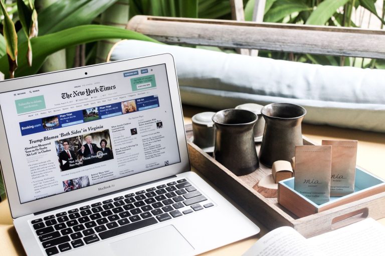 High angle of modern laptop with news on screen placed on table next to tin cups — I Wild Casino: 7 Dinge, die du wissen soll