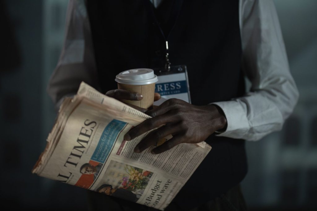 Close-up of a journalist holding a newspaper and coffee cup, conveying press and media concept. — Test xml