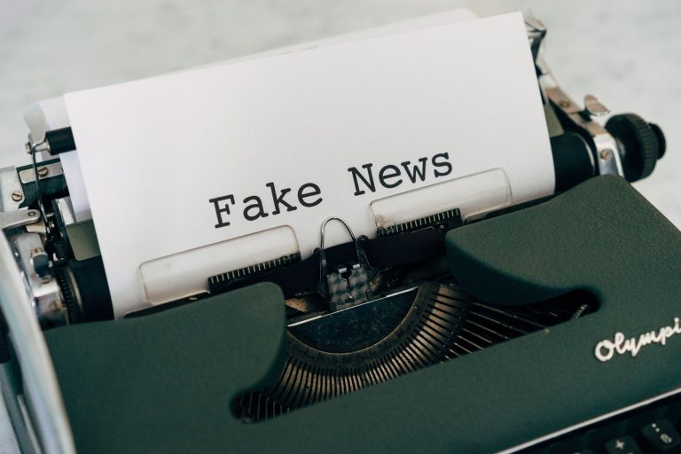 Close-up of vintage typewriter printing 'Fake News', depicting false information concepts. — Wie verifiziert man sein Konto b